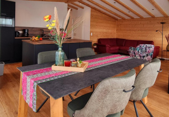 Helles Chalet Enzian bei Camping & Ferienpark Brilon mit moderner Küche, Esstisch und rotem Sofa.