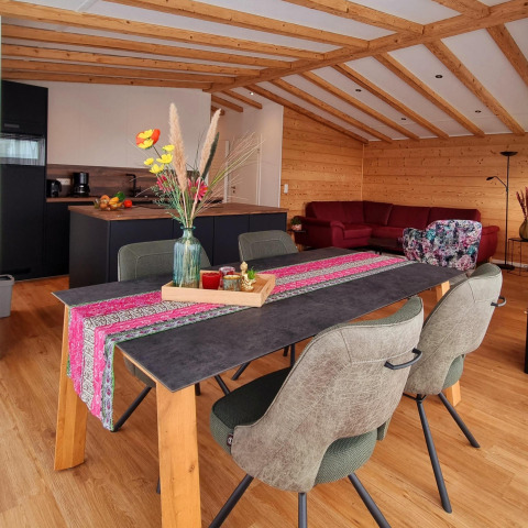 Acogedora zona común de Chalet Enzian en Camping & Ferienpark Brilon con mesa de comedor y cocina moderna.