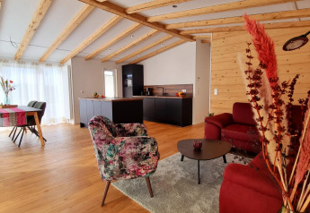 Modernes Chalet Enzian Wohnzimmer und Küche im Camping & Ferienpark Brilon mit Holzbalkendecke und stilvollem Design.