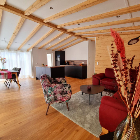 Salón y cocina modernos en Chalet Enzian, Camping & Ferienpark Brilon, con vigas de madera y decoración acogedora.