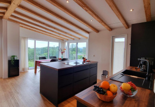 Cocina moderna y comedor en el Chalet Enzian en Camping & Ferienpark Brilon, Alemania, con vigas de madera.