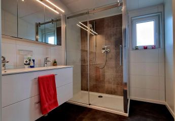 Moderne badkamer met douche, wit wastafelmeubel en spiegel in Chalet Enzian, Camping & Ferienpark Brilon, Duitsland.
