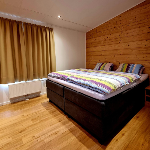 Dormitorio en Chalet Enzian en Camping & Ferienpark Brilon, Alemania, con cama doble y pared de madera.