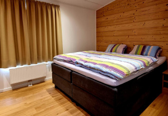 Dormitorio en Chalet Enzian en Camping & Ferienpark Brilon, Alemania, con cama doble y pared de madera.