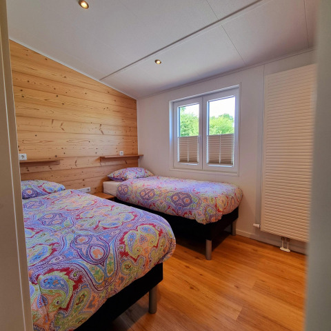 Dormitorio en Chalet Enzian en Camping & Ferienpark Brilon, Alemania, con dos camas y ropa de cama colorida.