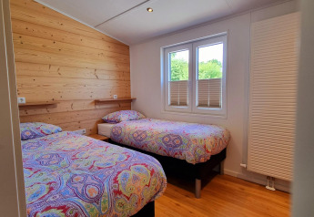 Dormitorio en Chalet Enzian en Camping & Ferienpark Brilon, Alemania, con dos camas y ropa de cama colorida.