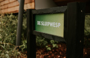Schild mit der Aufschrift 'De Sluipwesp' bei Skycabin im Naturhaus auf Camping Si-Es-An in den Niederlanden.