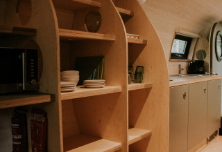 Estanterías de madera y cocina moderna en Skycabin, una casa natural en Camping Si-Es-An, Países Bajos.