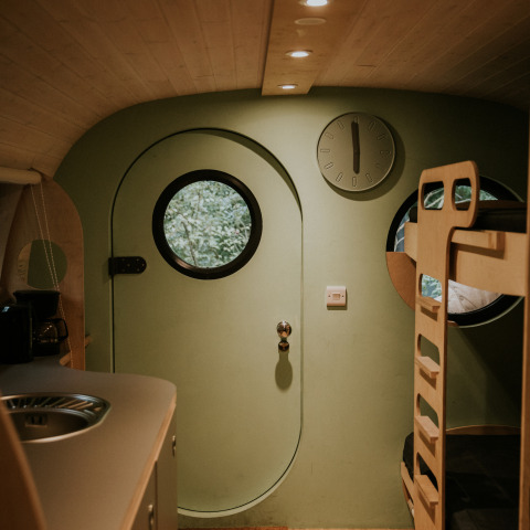 Interior de una Skycabin en Camping Si-Es-An, Países Bajos, con ventanas redondas y literas modernas.