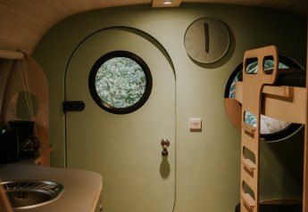 Interior de una Skycabin en Camping Si-Es-An, Países Bajos, con ventanas redondas y literas modernas.