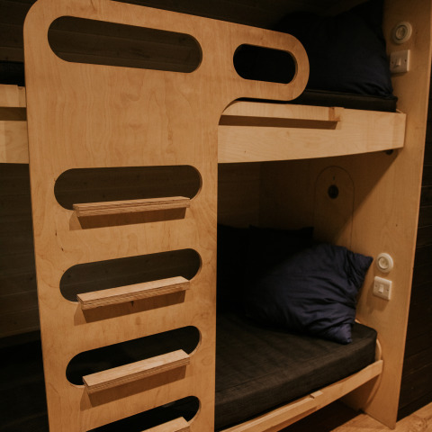 Litera moderna de madera con ropa de cama oscura, en Skycabin, Nature house, Camping Si-Es-An, Países Bajos.