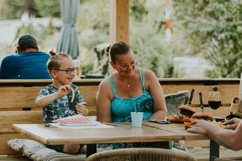 Una familia feliz disfruta de una comida al aire libre en Skycabin, una casa naturaleza en Camping Si-Es-An.