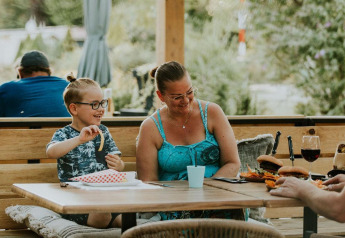 Una familia feliz disfruta de una comida al aire libre en Skycabin, una casa naturaleza en Camping Si-Es-An.