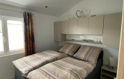 Dormitorio con cama doble, ropa de cama a rayas, armarios superiores y ventana en Chalet Waldfee, Alemania.