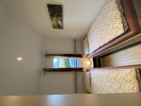 Dormitorio con dos camas individuales y ventana en Chalet Waldfee, Camping & Ferienpark Brilon, Alemania.