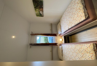 Dormitorio con dos camas individuales y ventana en Chalet Waldfee, Camping & Ferienpark Brilon, Alemania.