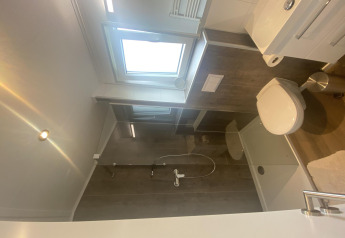 Baño moderno con ducha, inodoro, lavabo y ventana en Chalet Waldfee, Camping & Ferienpark Brilon, Alemania.