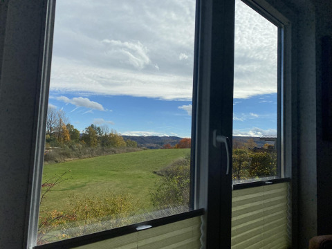 Vista su campi verdi e colline da una finestra dello Chalet Waldfee, Camping & Ferienpark Brilon, Germania.