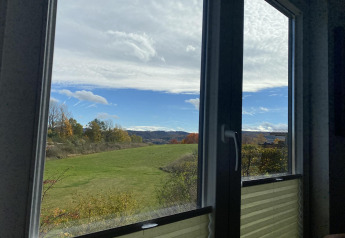 Vista de campos verdes y colinas desde una ventana en Chalet Waldfee, Camping & Ferienpark Brilon, Alemania.
