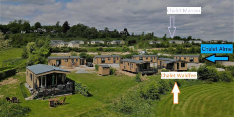 Vista de cabañas en Camping & Ferienpark Brilon, Alemania, tomada desde Chalet Waldfee con letreros visibles.