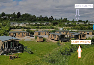 Vista de cabañas en Camping & Ferienpark Brilon, Alemania, tomada desde Chalet Waldfee con letreros visibles.