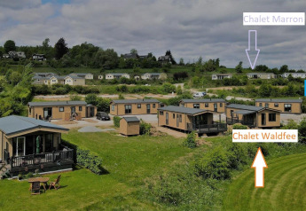 Vista de cabañas en Camping & Ferienpark Brilon, Alemania, tomada desde Chalet Waldfee con letreros visibles.