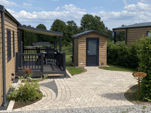 Vista exterior del Chalet Waldfee en Camping & Ferienpark Brilon, Alemania, con terraza y sendero.