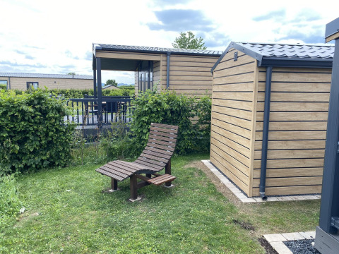 Chalet Waldfee en Camping & Ferienpark Brilon, Alemania, con silla de madera y cabañas modernas.