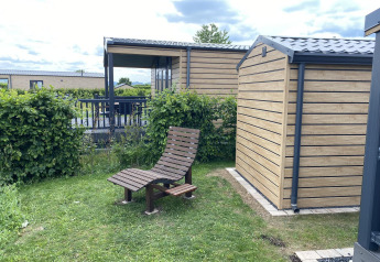 Chalet Waldfee en Camping & Ferienpark Brilon, Alemania, con silla de madera y cabañas modernas.