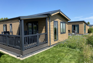 Chalet de madera en Camping & Ferienpark Brilon, Alemania, en un día soleado con césped y flores silvestres.