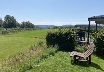 Día soleado en Chalet Waldfee en Camping & Ferienpark Brilon, Alemania, con vistas a campos y colinas verdes.