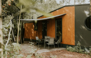 Vista exterior de Happy Bee Lodge en Camping Si-Es-An, Países Bajos, rodeada de árboles verdes.