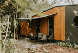 Buitenbeeld van Happy Bee Lodge op Camping Si-Es-An in Nederland, tussen het groen en de bomen.