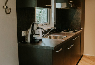 Cocina moderna en Happy Bee Lodge, Camping Si-Es-An, Países Bajos, con hervidor y fregadero.