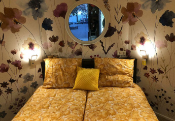 Camera da letto al Happy bee lodge, Camping Si-Es-An, Paesi Bassi, con biancheria gialla e carta da parati floreale.