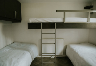 Driepersoonskamer met twee enkele bedden en een stapelbed in Happy bee lodge, Camping Si-Es-An, Nederland.