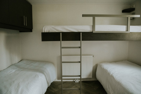 Dreibettzimmer mit zwei Einzelbetten und einem Hochbett im Happy bee lodge, Camping Si-Es-An, Niederlande.