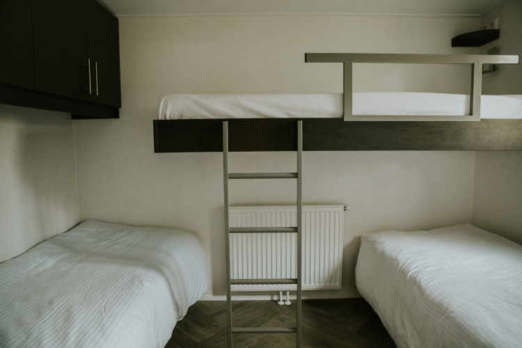 Habitación triple con dos camas individuales y una litera en Happy bee lodge, Camping Si-Es-An, Países Bajos.