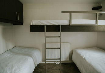 Camera tripla con due letti singoli e un letto a castello presso Happy bee lodge, Camping Si-Es-An, Paesi Bassi.