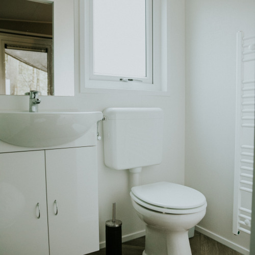 Baño moderno y luminoso con inodoro y lavabo en Happy Bee Lodge, Camping Si-Es-An, Países Bajos.