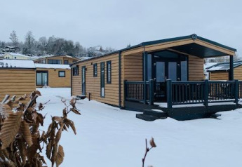 Chalets en bois sous la neige à Chalet Bergrose, Camping & Ferienpark Brilon, Allemagne, en hiver.