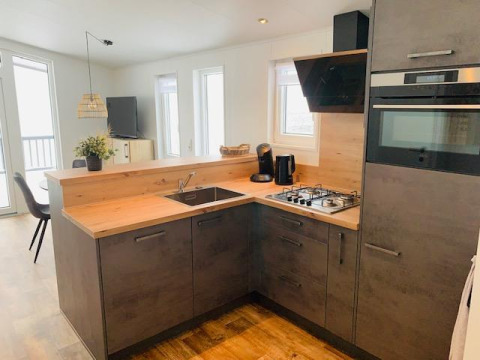 Cucina moderna con piano in legno, forno e grandi finestre presso Chalet Bergrose, Camping Brilon, Germania.