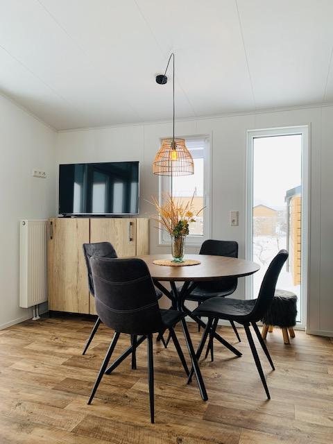 Comedor moderno en Chalet Bergrose, Camping & Ferienpark Brilon, Alemania, con muebles de madera y televisor.