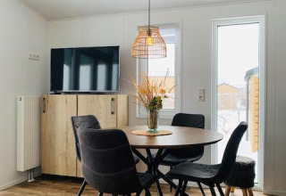 Comedor moderno en Chalet Bergrose, Camping & Ferienpark Brilon, Alemania, con muebles de madera y televisor.