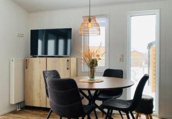 Comedor moderno en Chalet Bergrose, Camping & Ferienpark Brilon, Alemania, con muebles de madera y televisor.