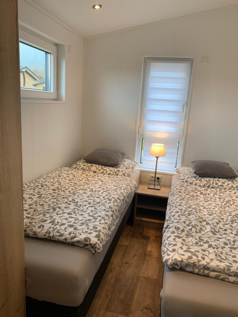 Dormitorio en Chalet Bergrose, Camping & Ferienpark Brilon, Alemania, con dos camas individuales y mesilla.