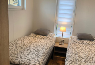 Dormitorio en Chalet Bergrose, Camping & Ferienpark Brilon, Alemania, con dos camas individuales y mesilla.