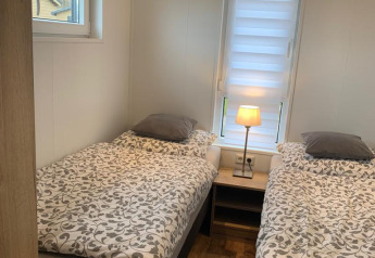 Dormitorio en Chalet Bergrose, Camping & Ferienpark Brilon, Alemania, con dos camas individuales y mesilla.