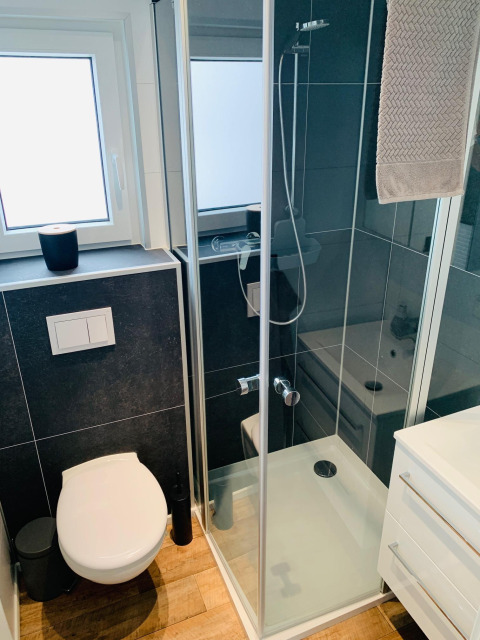Bagno moderno e compatto con doccia, WC e finestra nel Chalet Bergrose al Camping & Ferienpark Brilon, Germania.