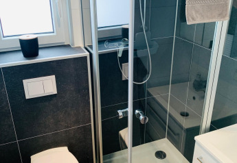 Salle de bain moderne et compacte avec douche, toilettes et fenêtre au Chalet Bergrose, Camping & Ferienpark Brilon, Allemagne.